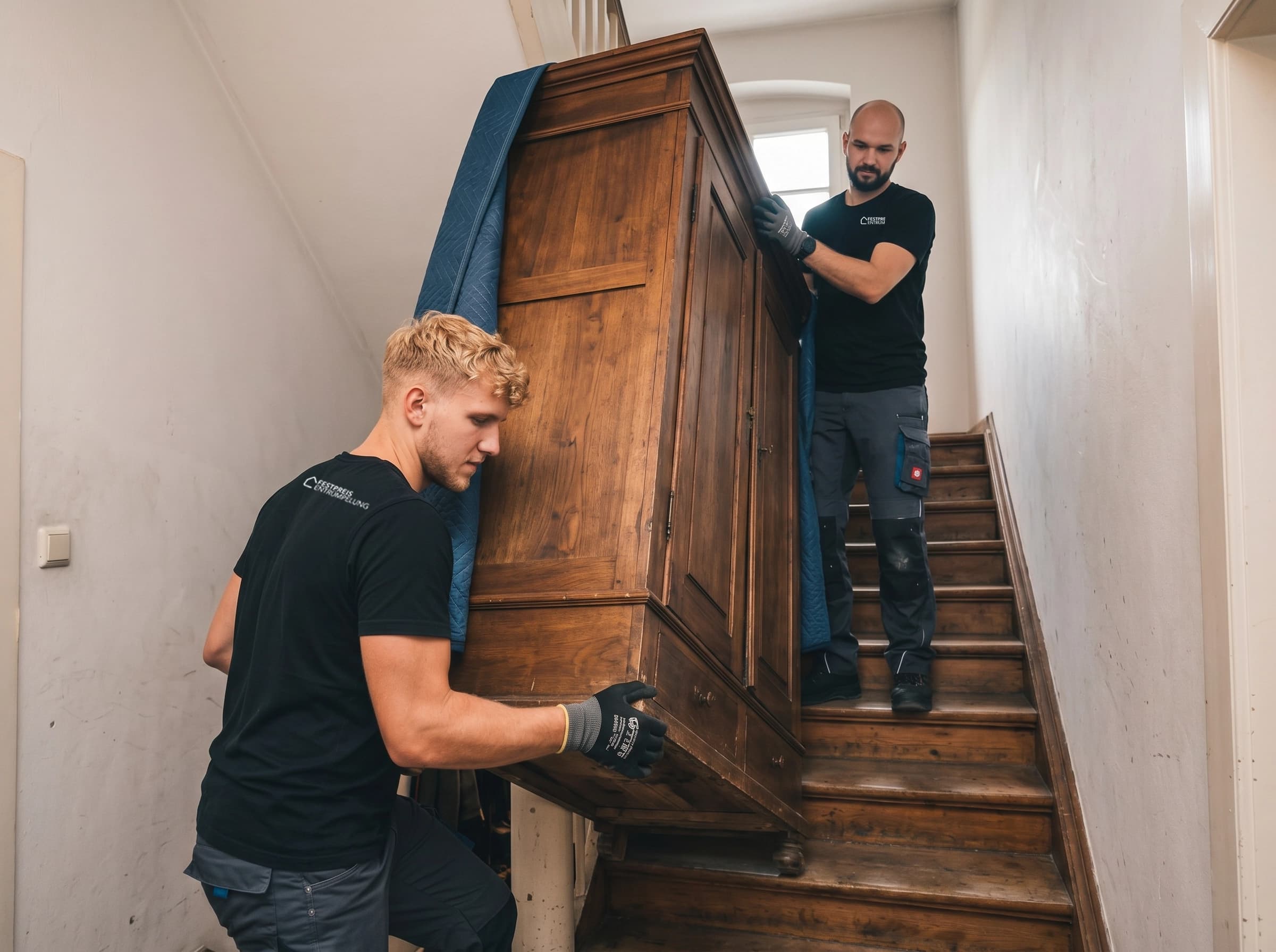 Team trägt schweren Wandschrank die Treppe hinunter